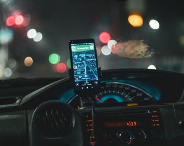 Close-up of a smartphone with map navigation in a car at night with bokeh effect.